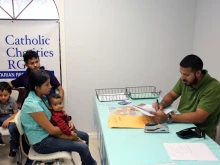 August 17, 2017 - A volunteer at the Catholic Charities Humanitarian Respite Center in McAllen helps a Central American refugee family take a bus to go stay with U.S. family